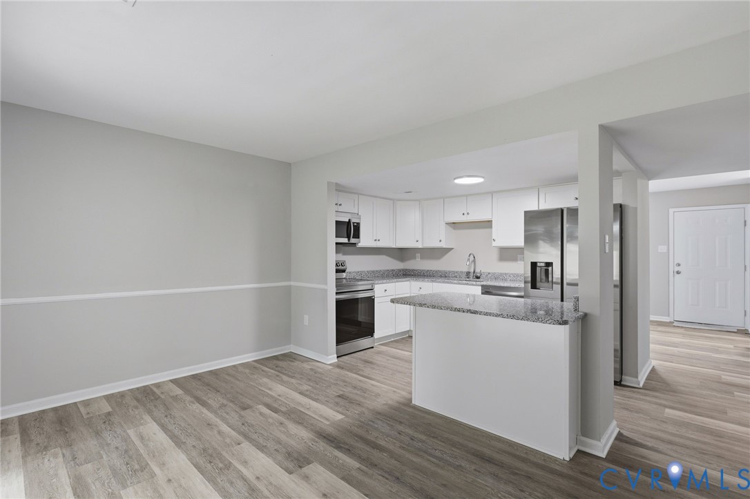 Modern kitchen featuring white cabinetry, granite countertops, and stainless steel appliances