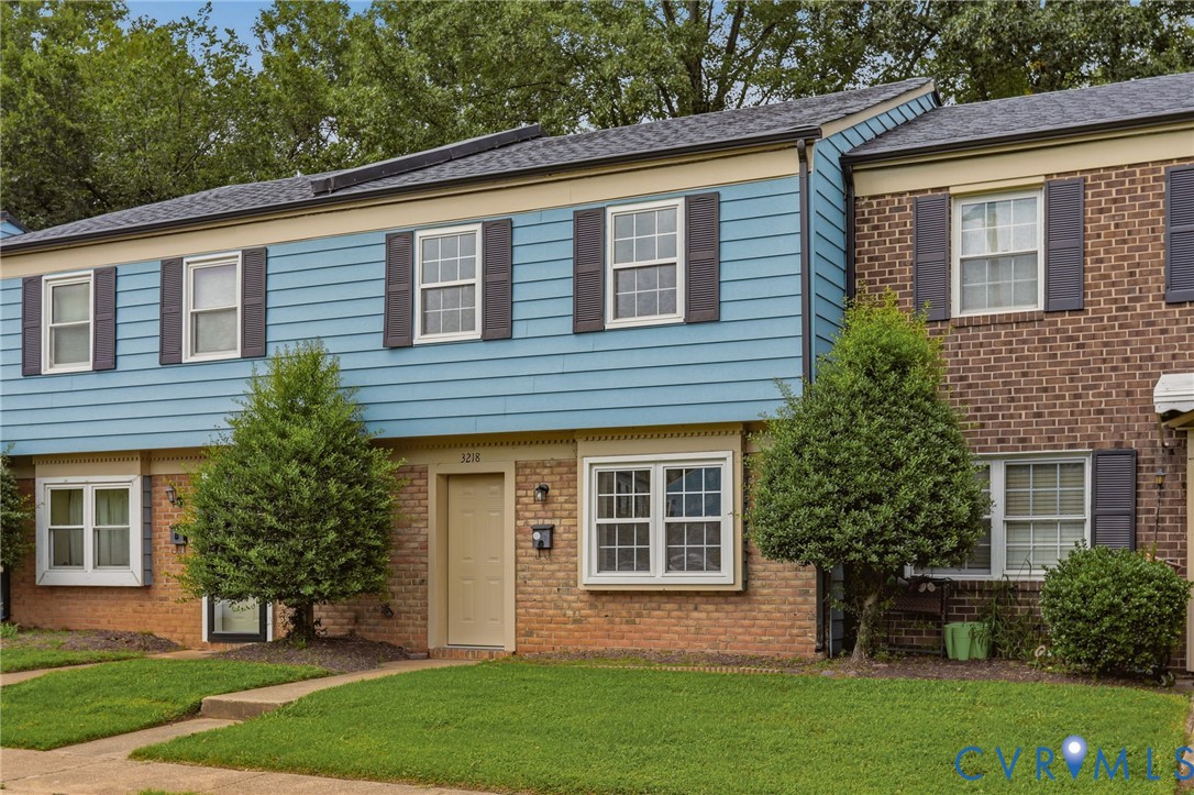 Two-story residence featuring brick and horizontal siding, dark shutters, and a front entry door with transom window
