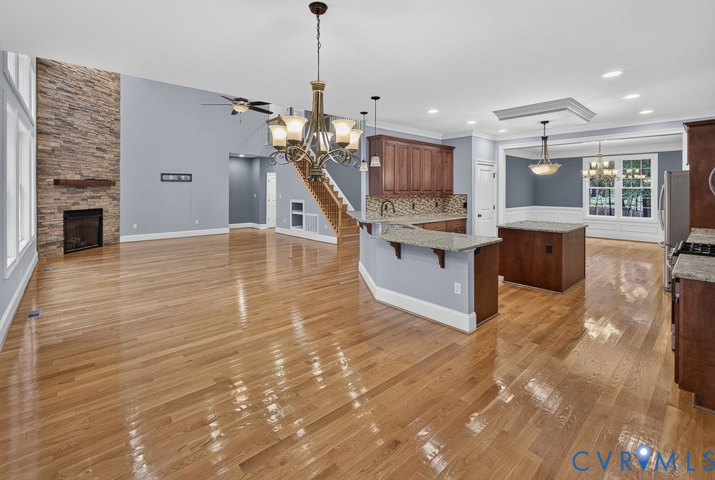 Hardwood flooring throughout, a stone-accented fireplace with wood mantel, a kitchen island with granite countertops, and a built-in kitchen island