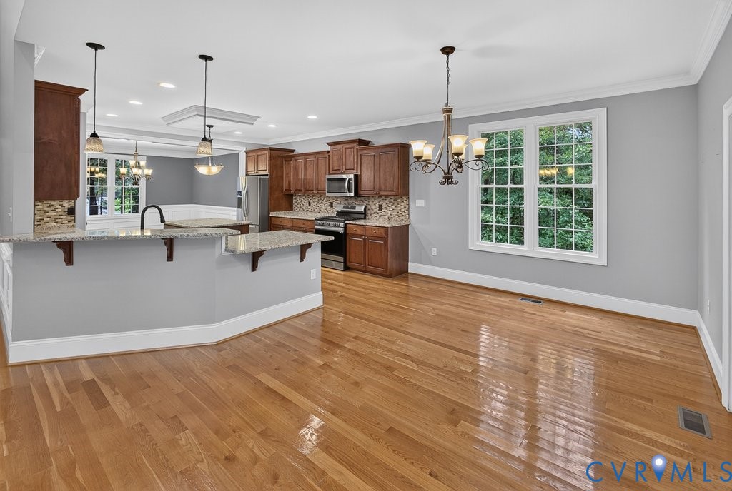 Hardwood flooring throughout, kitchen with wood cabinetry, stainless steel appliances, and a tiled backsplash