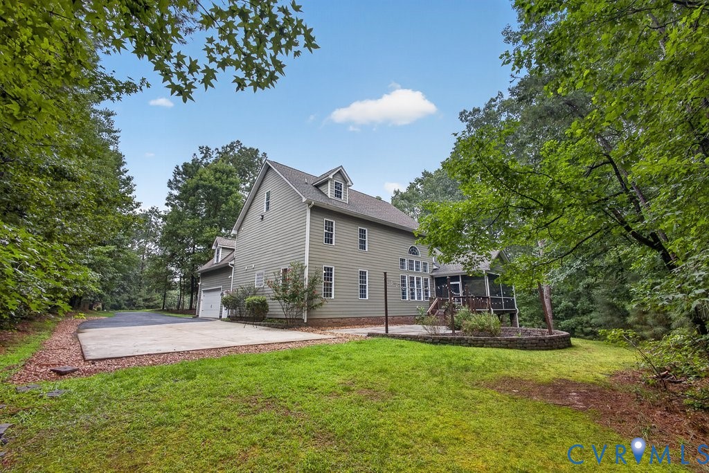 Two-story siding exterior with multiple dormer windows, attached garage, screened porch, and a stone-edged planting bed