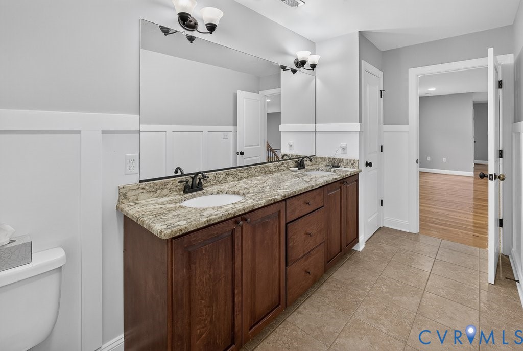 Dual vanity with a stone countertop, integral sinks, and dark wood-finish cabinetry