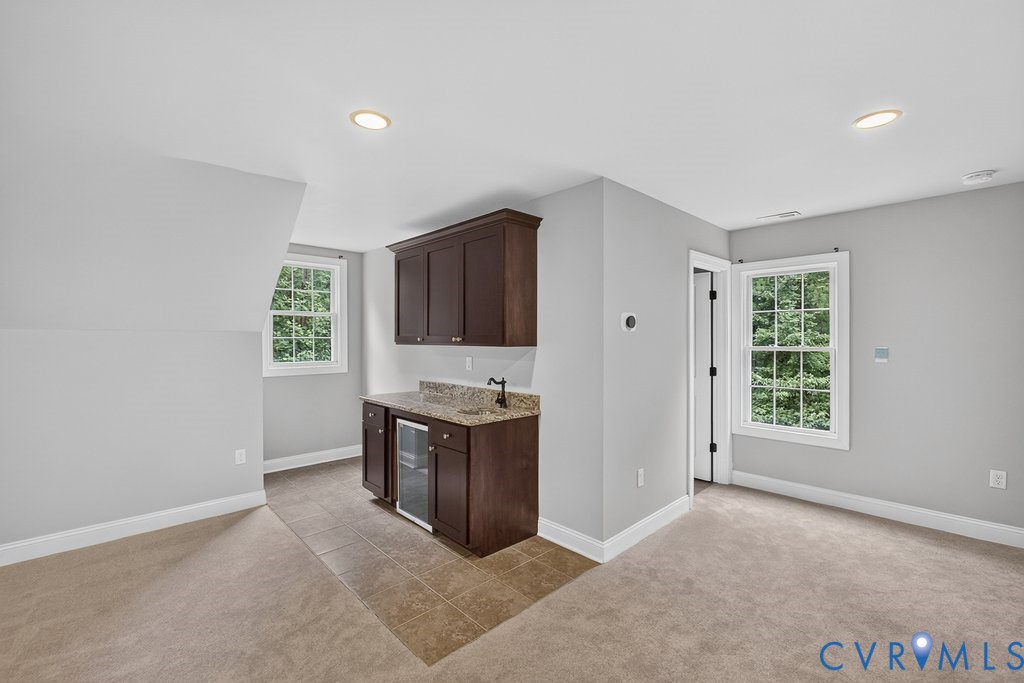 Built-in wet bar with dark wood cabinetry, granite-style countertop, and integrated beverage cooler