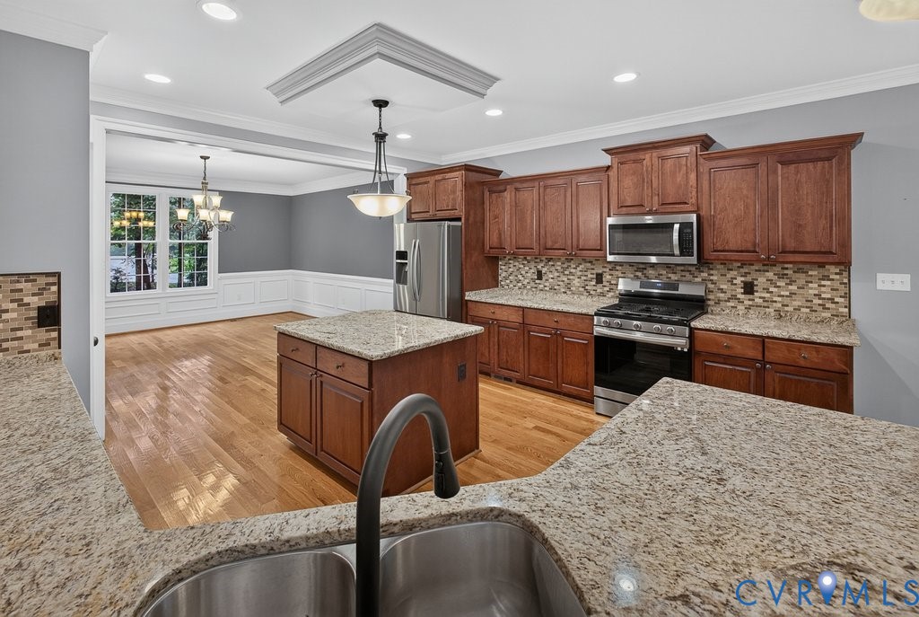 Kitchen featuring wood cabinetry, stainless steel appliances, granite countertops, and a decorative tile backsplash