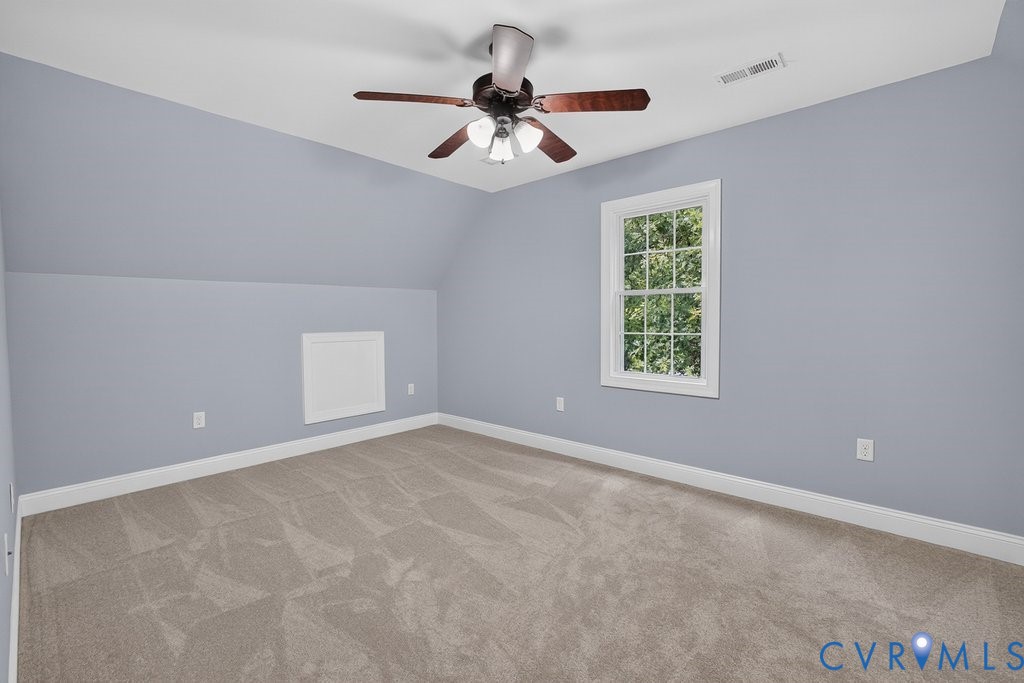 Light gray walls with sloped ceiling details, a white-framed multi-pane window, and a ceiling fan with light fixture