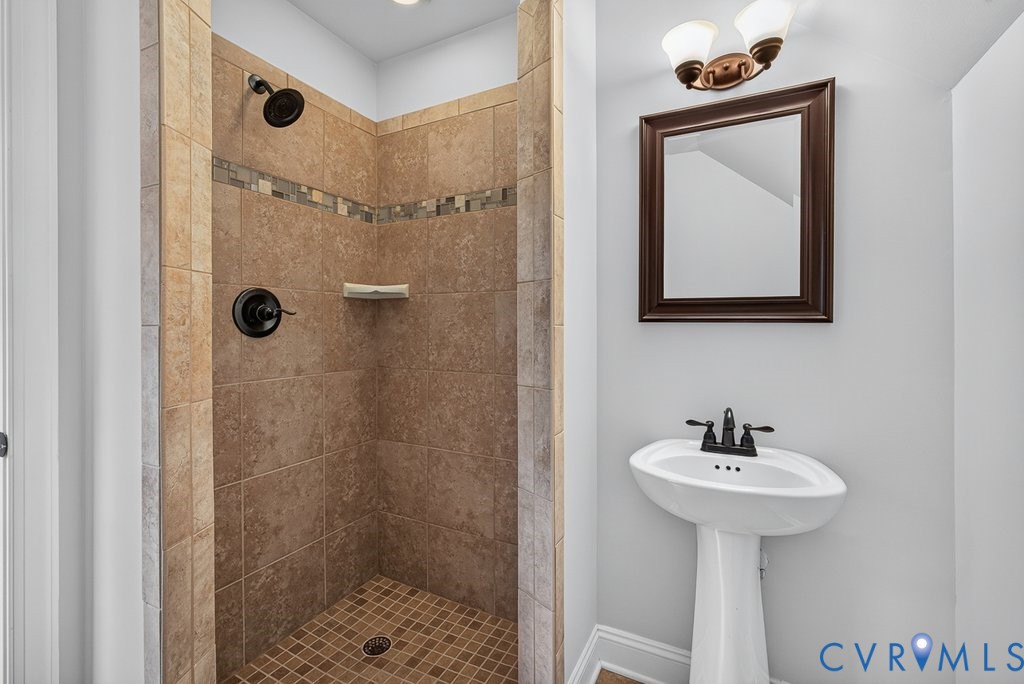 Shower with tiled walls and mosaic accent, dark bronze fixtures, and a coordinating pedestal sink with dark bronze faucet