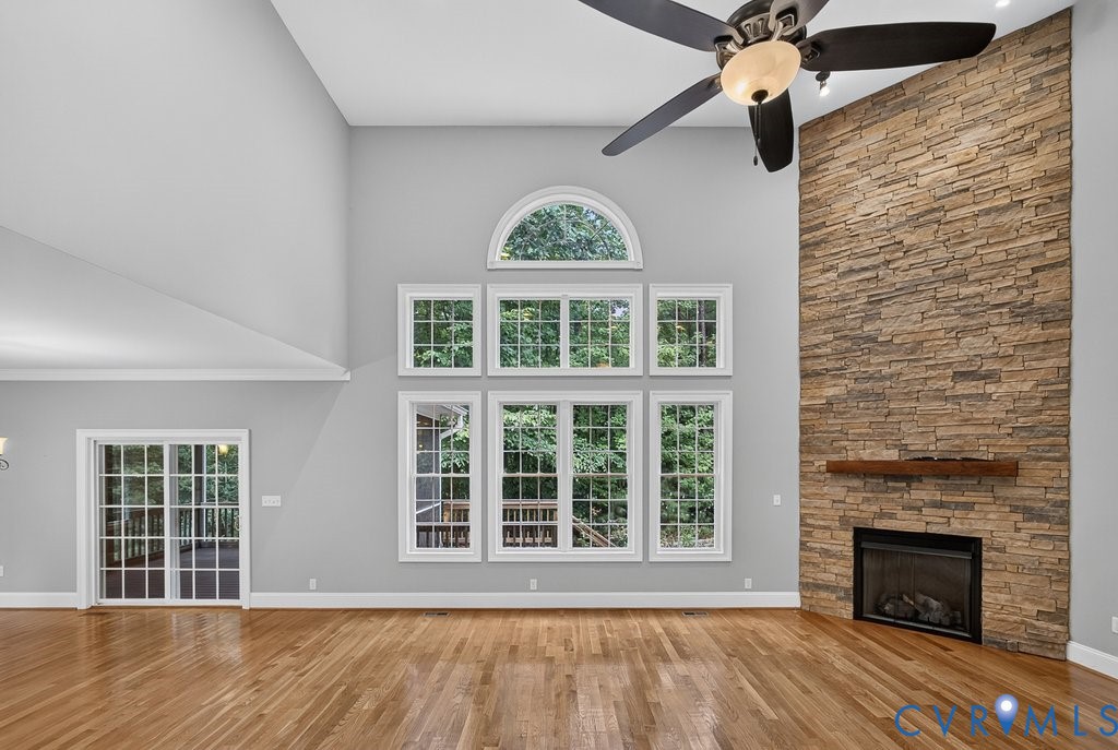 Soaring two-story great room with cathedral ceiling and ceiling fan, anchored by a striking brick fireplace with dark surround