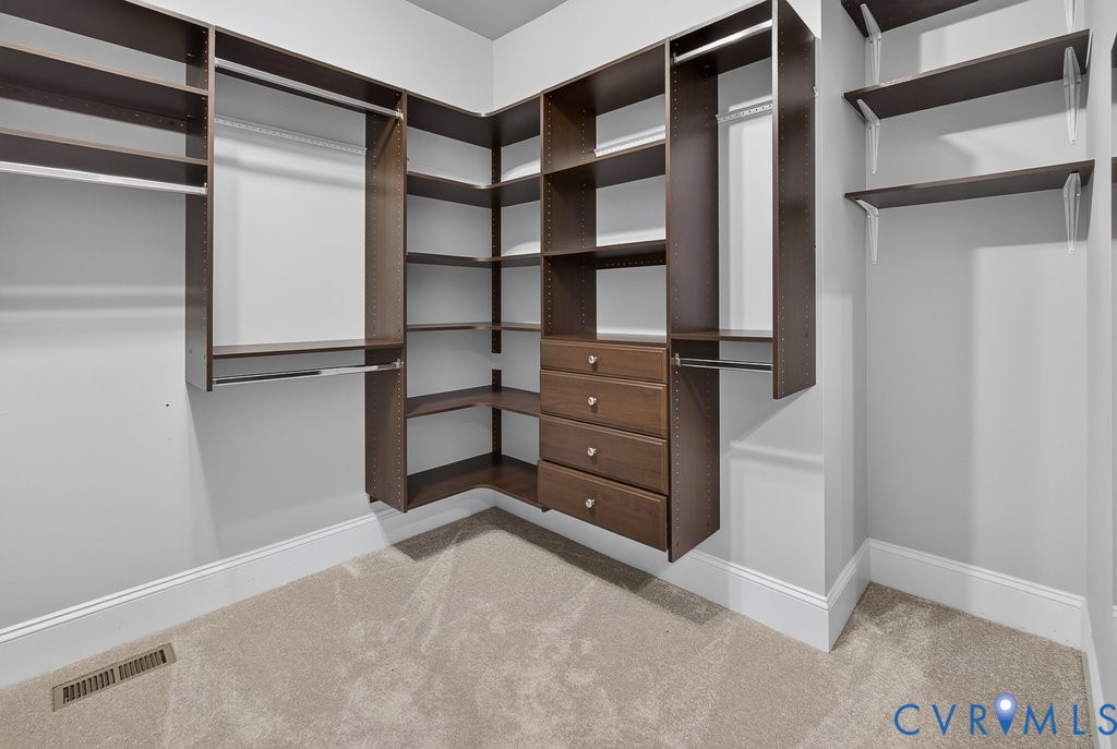 Custom closet system featuring dark wood-finish cabinetry, built-in shelving, multiple hanging rods, and integrated drawers