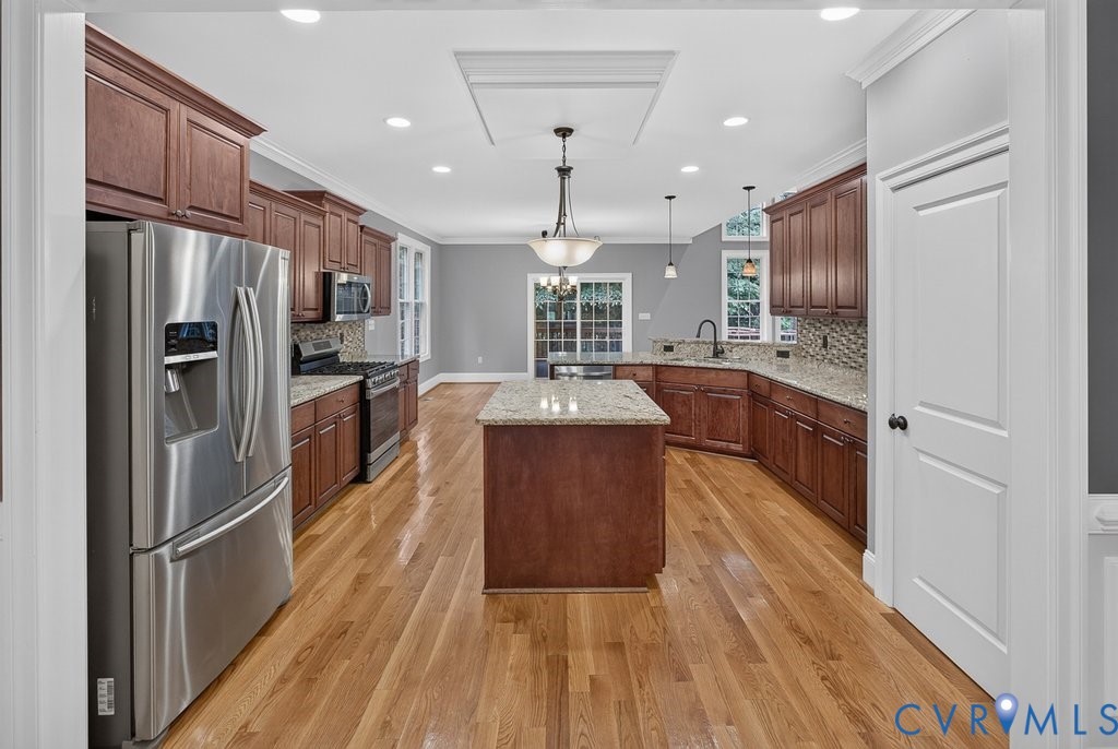 Hardwood flooring, stainless steel appliances, central kitchen island, wood-finish cabinetry, and recessed lighting