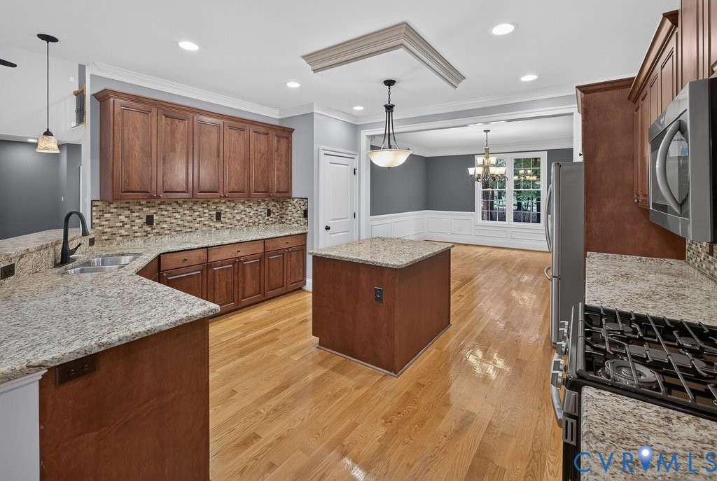 Kitchen featuring granite countertops, wood-finish flooring, wood cabinetry, a built-in microwave, and a gas range