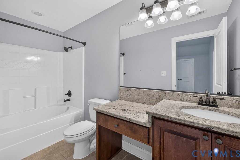 Granite vanity countertop with an integrated sink, dark wood-finish cabinetry, and a full-width mirror
