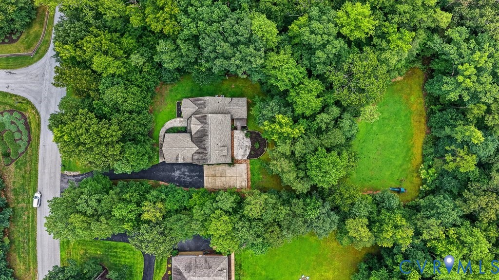 Aerial view showcasing a substantial stone residence nestled within mature landscaping and lush grounds