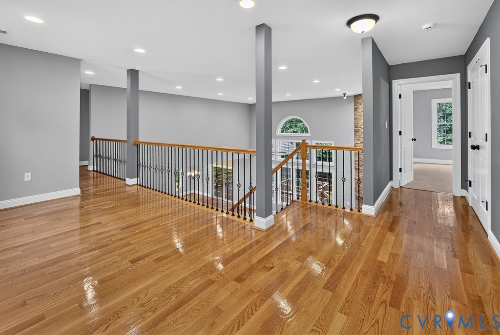 Hardwood flooring, recessed ceiling lighting, wrought iron balusters, arched window, and paneled interior doors