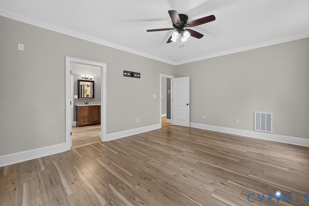 Wood-finish flooring, crown molding, and a ceiling fan with integrated lighting