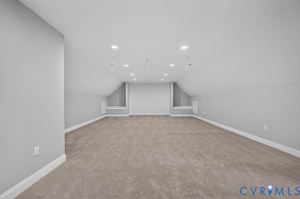 Spacious room featuring carpeting, recessed lighting, and sloped ceilings