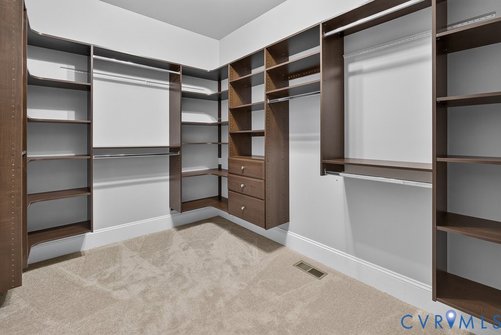 Custom closet system featuring wood-finish shelving, multiple hanging rods, and built-in drawers