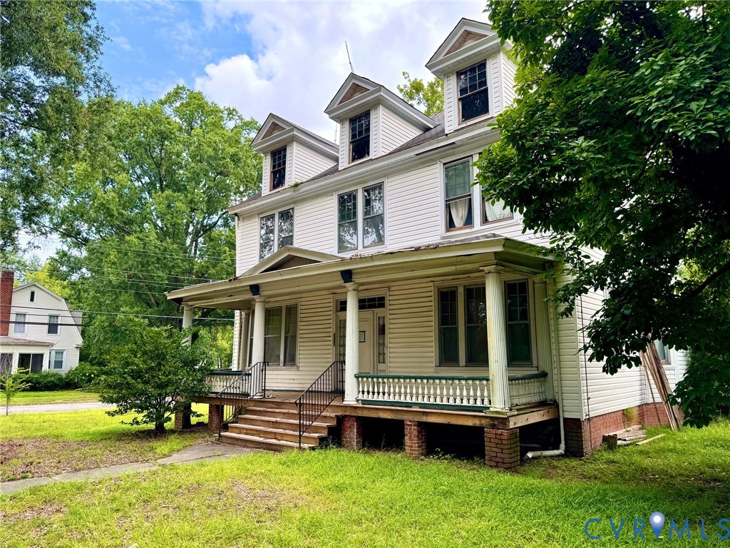 Three-story residence featuring white siding and a covered porch with round columns