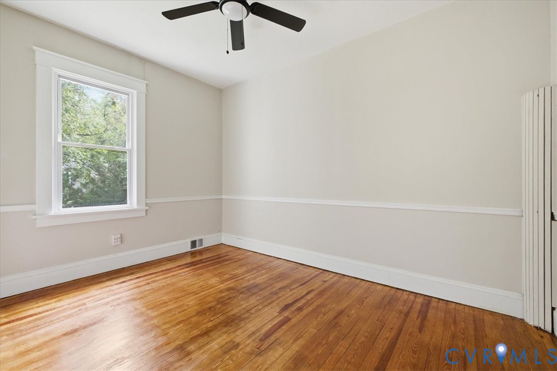 Wood-finish flooring, white trim, and a ceiling fan