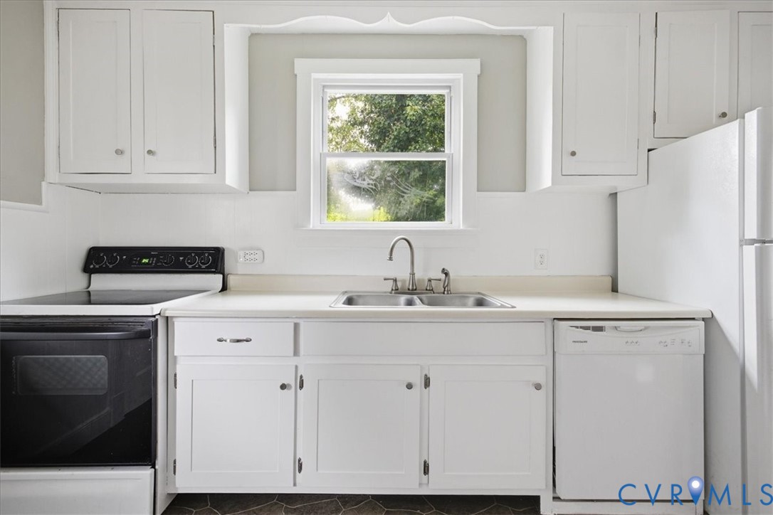Kitchen featuring white cabinetry, a double basin sink, and a black electric range