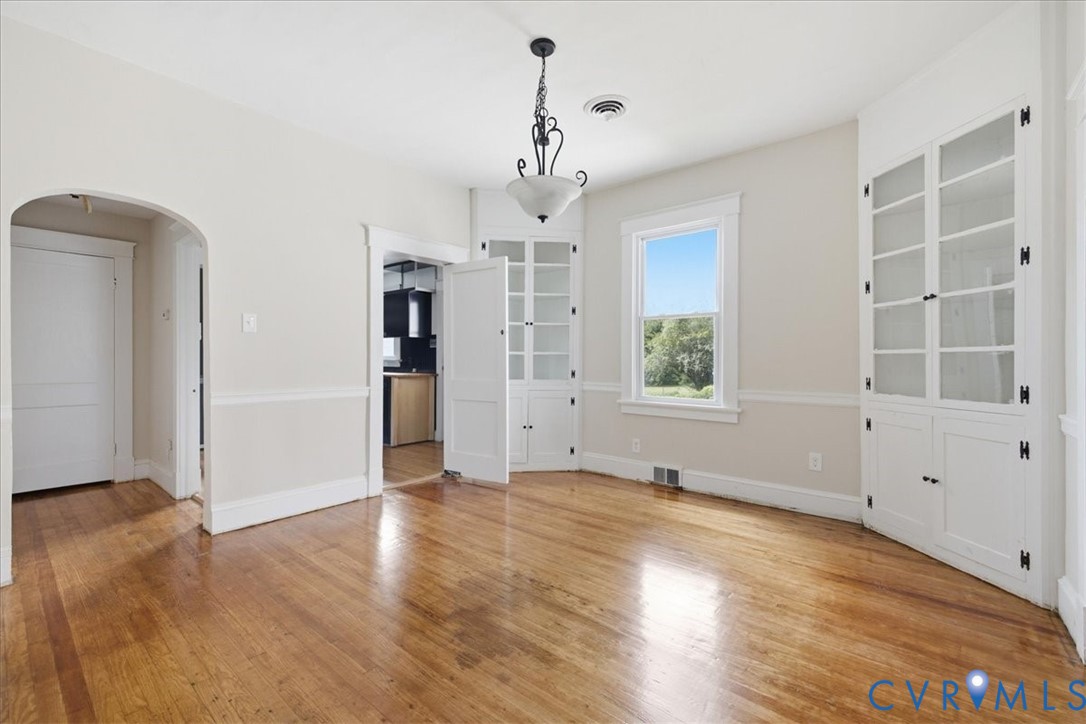 Hardwood flooring, painted walls with chair rail trim, built-in display cabinetry, and a central light fixture