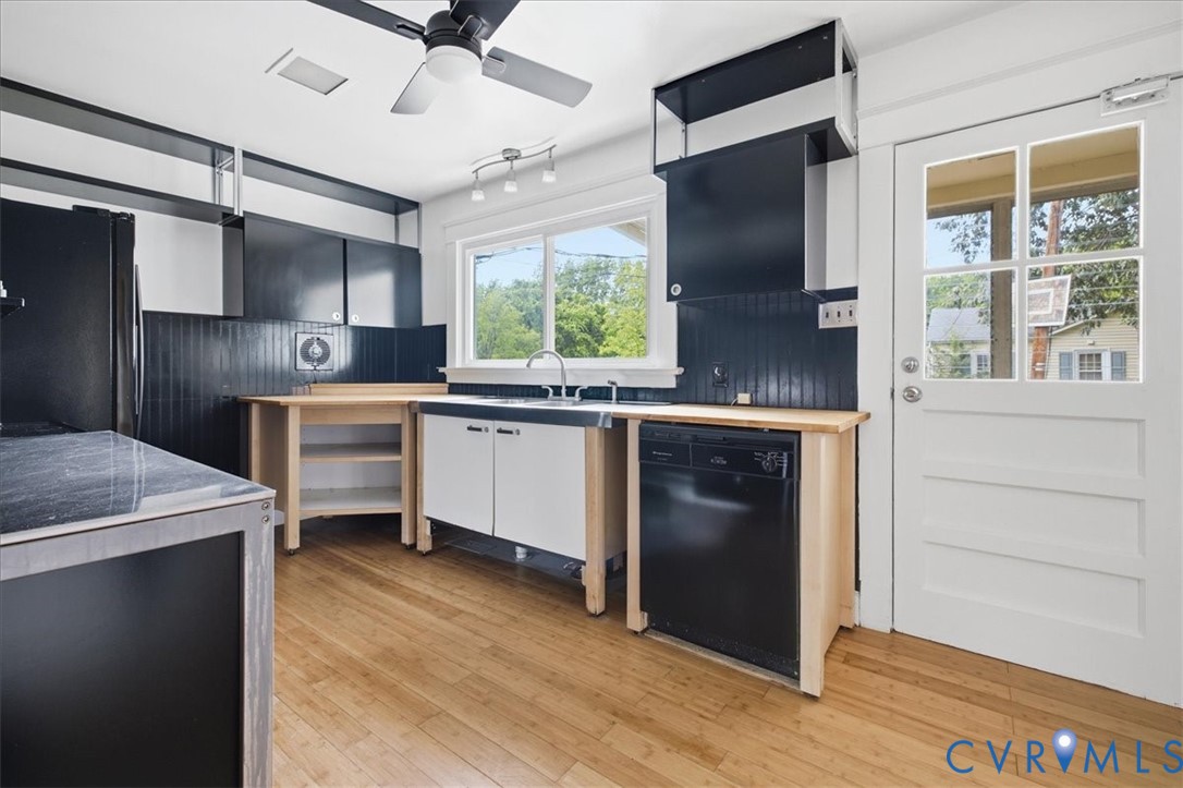 Contemporary kitchen featuring custom wood-finish cabinetry with integrated black appliances, stainless steel sink with professional faucet, and wood-finish flooring throughout