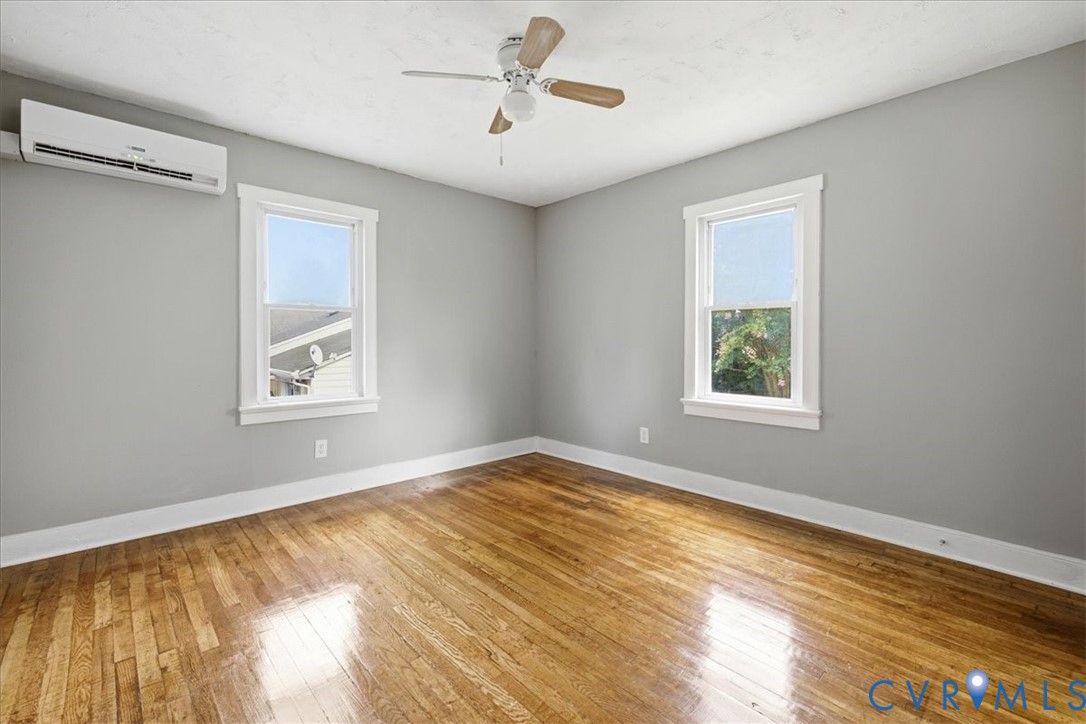 Hardwood flooring, painted walls, ceiling fan, white trim, and a split-system air conditioning unit