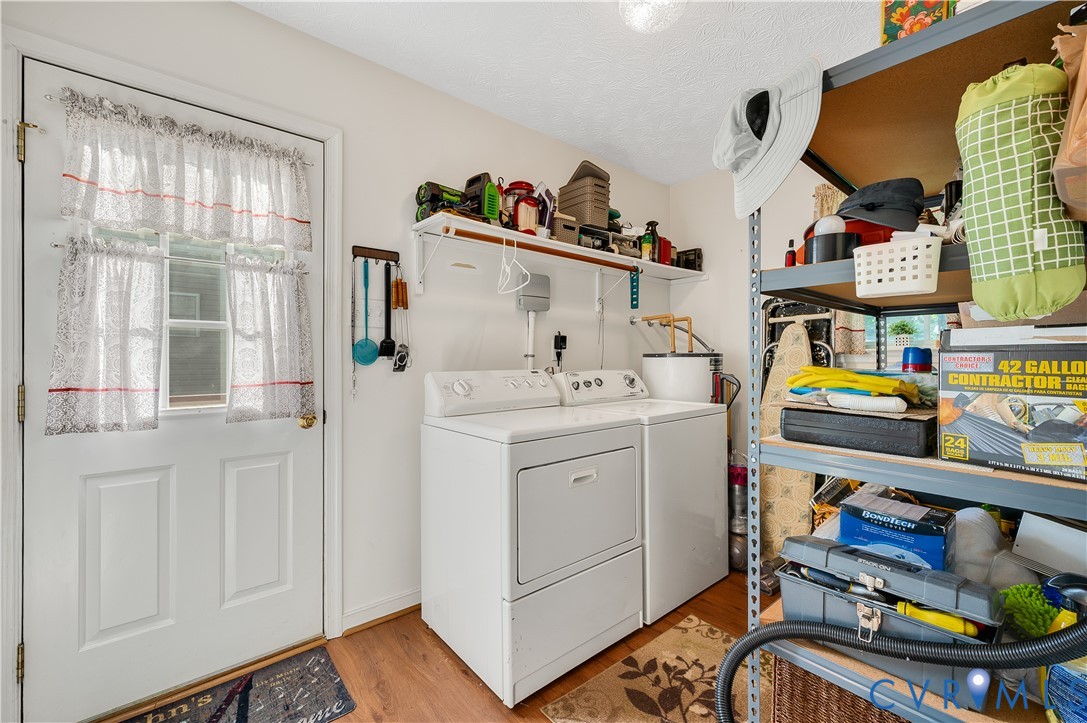 Utility room featuring side-by-side washer and dryer with white enamel finish, wood-finish flooring, and extensive built-in shelving with organized storage throughout