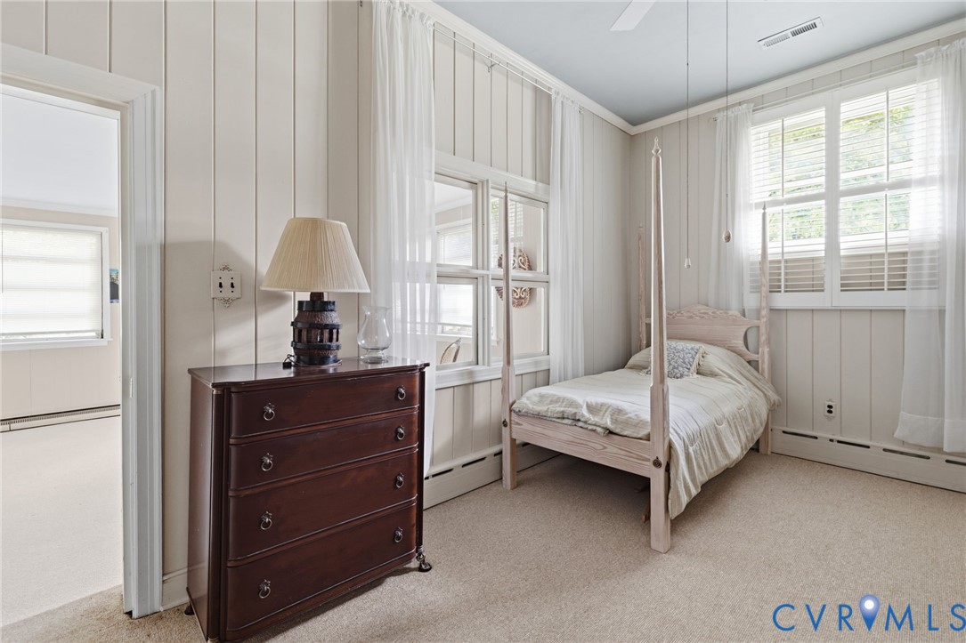 Soft neutral carpet flooring, vertical paneling walls, and multiple windows with white blinds