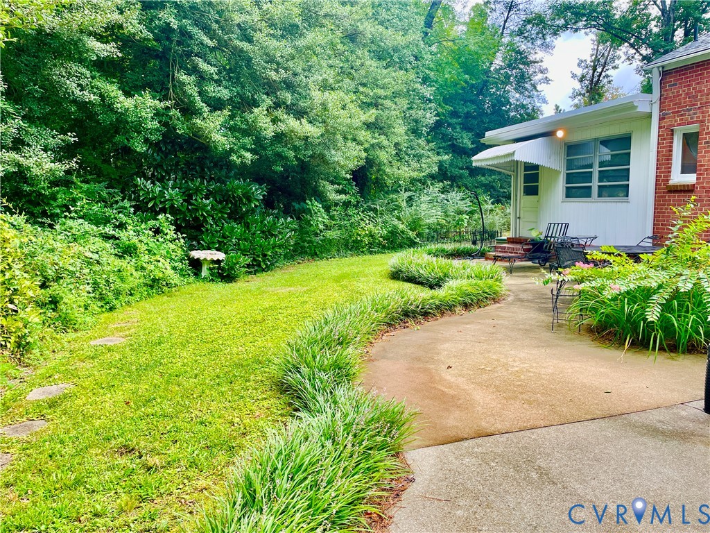 Expansive lawn with a concrete patio and a curved walkway