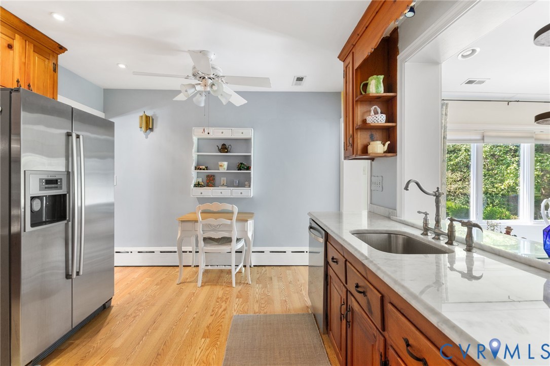 Hardwood flooring complements the wood-finish cabinetry, marble counter tops, stainless steel refrigerator, and built-in dishwasher
