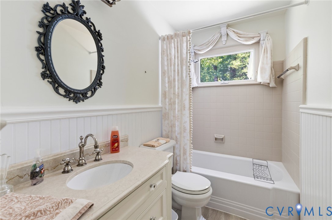 White beadboard wainscoting, solid surface countertop, undermount sink, classic brushed nickel faucet, and a tiled shower/tub combination