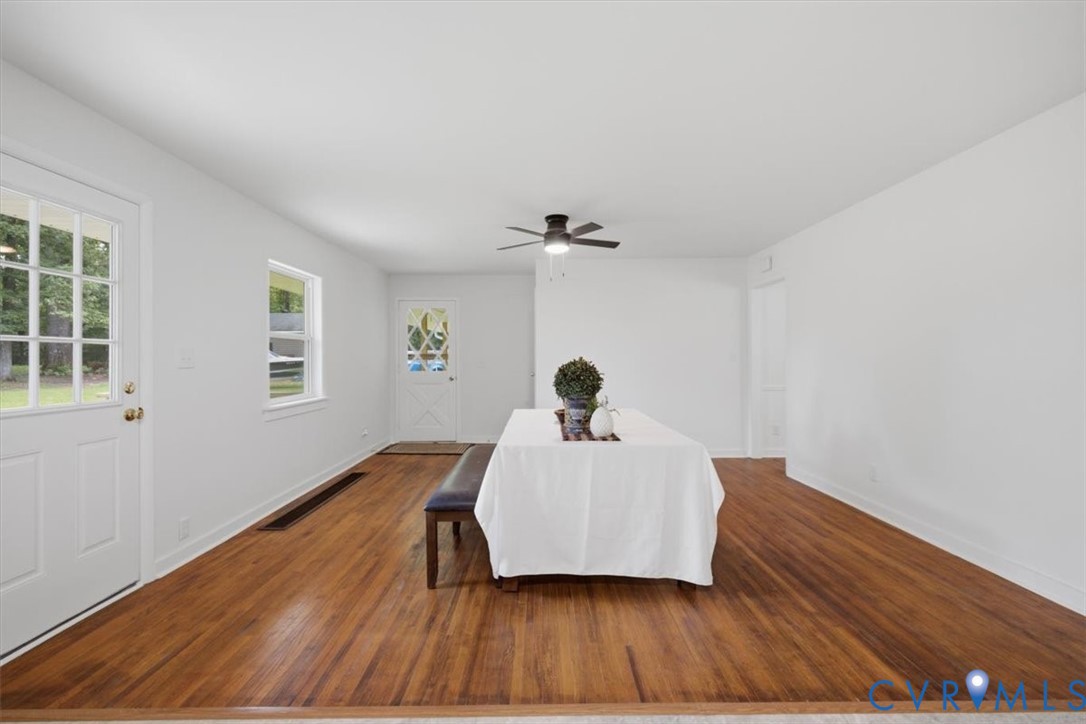 Hardwood flooring, white painted walls, white trim, ceiling fan, and multiple windows with natural light