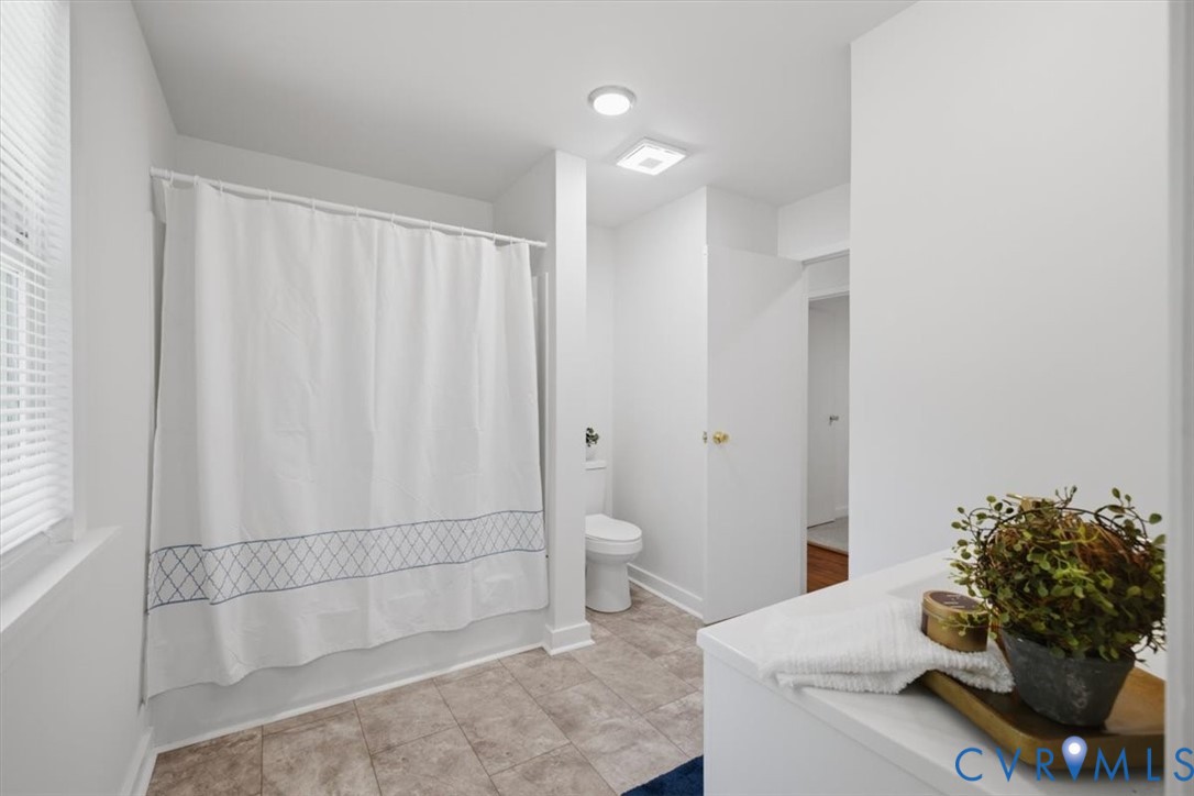 Full bathroom with tiled flooring, a shower-tub combination, and a single window