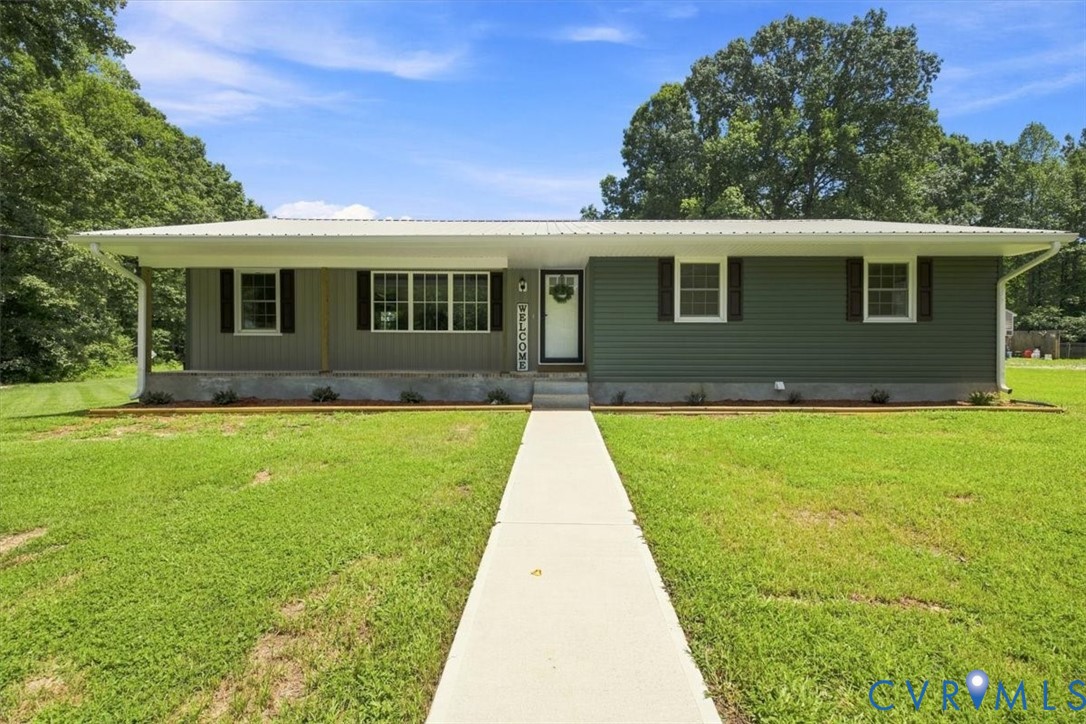 Siding exterior with multiple window styles, covered front porch, concrete walkway, and a metal roof