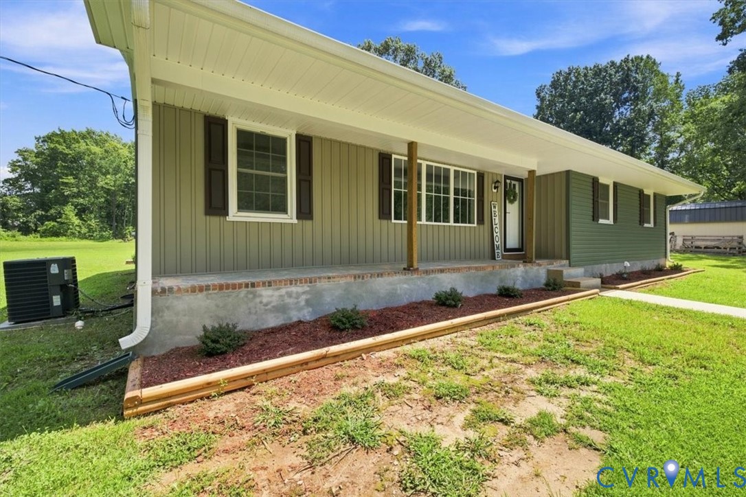 Exterior featuring horizontal siding, dark shutters, covered front porch, and landscaped planting beds