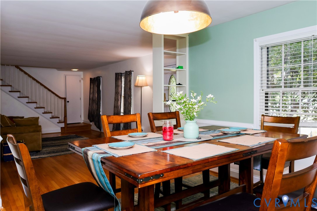 Dining area with wood-finish flooring, built-in shelving, and natural light from a window with blinds Dining area with wood-finish flooring, built-in shelving, and natural light from a window with blinds