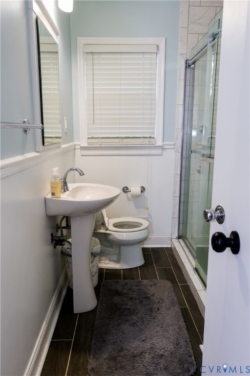 Pedestal sink with chrome faucet, glass-enclosed shower, and tile floors.