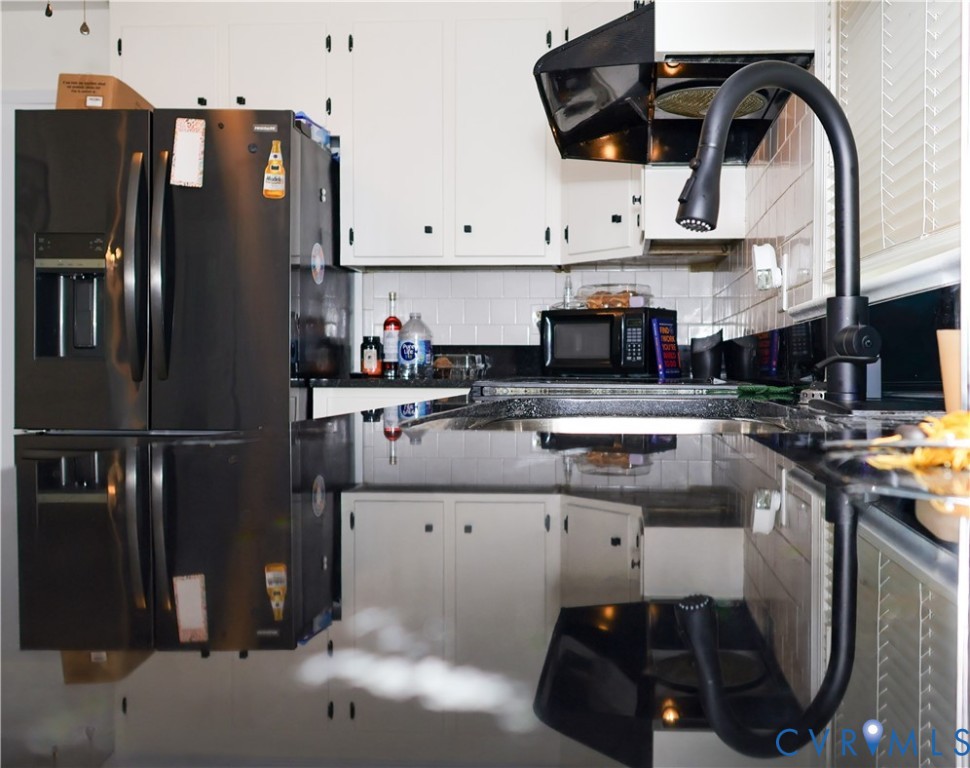 Contemporary kitchen featuring white cabinetry, black granite countertops, and a black gooseneck faucet