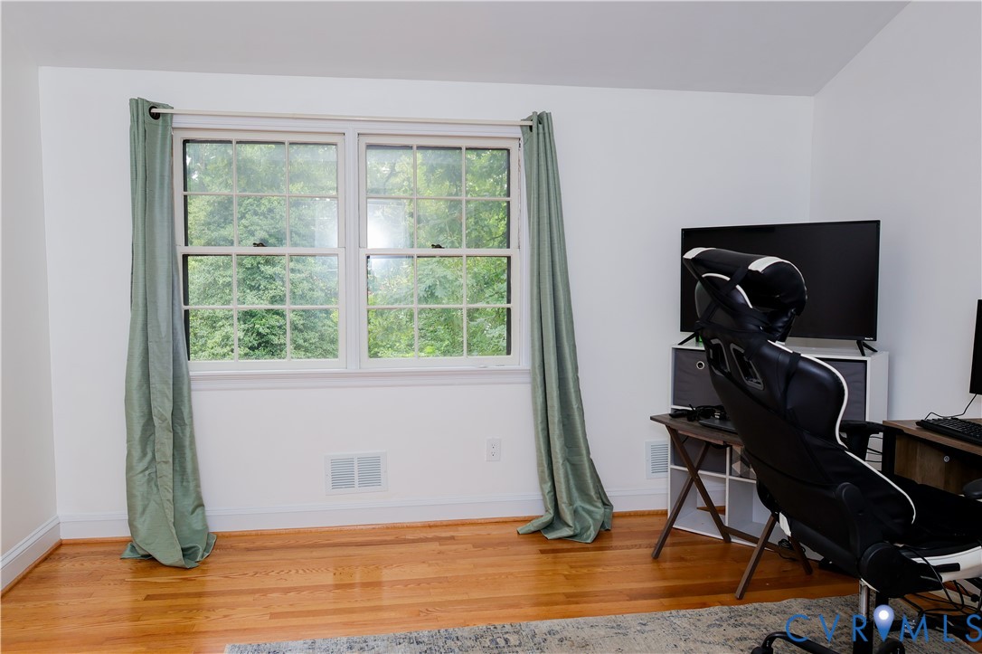 Third bedroom or office w/ Hardwood flooring and a double-hung window with grilles
