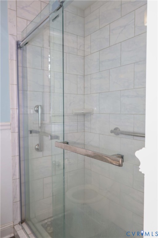 Glass-enclosed shower with tile walls.