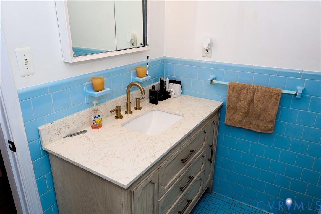 Bathroom vanity with a white countertop and integrated sink, complemented by a gold-finish faucet