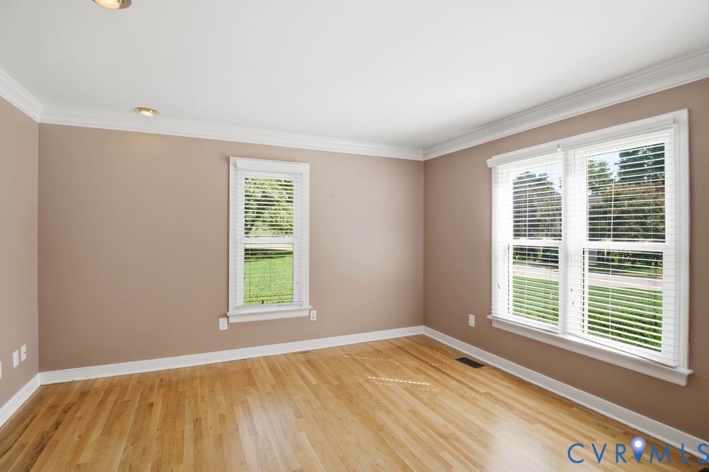 Hardwood flooring, painted walls, white crown molding, recessed lighting, and multiple windows