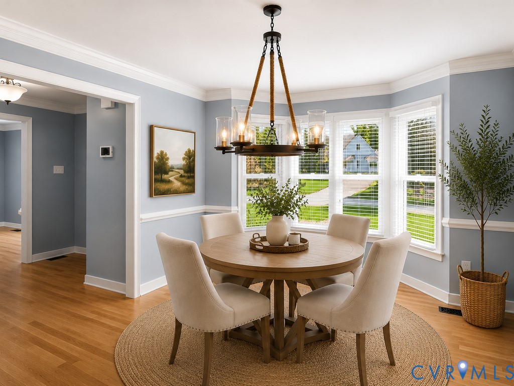 Dining area featuring wood-finish flooring, a contemporary chandelier, and a bay window with multiple panes