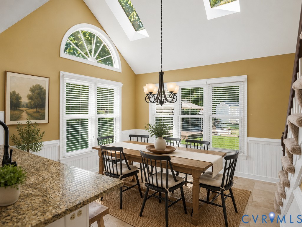 Vaulted ceiling with skylights, arched window, beadboard wainscoting, and a granite-finish countertop