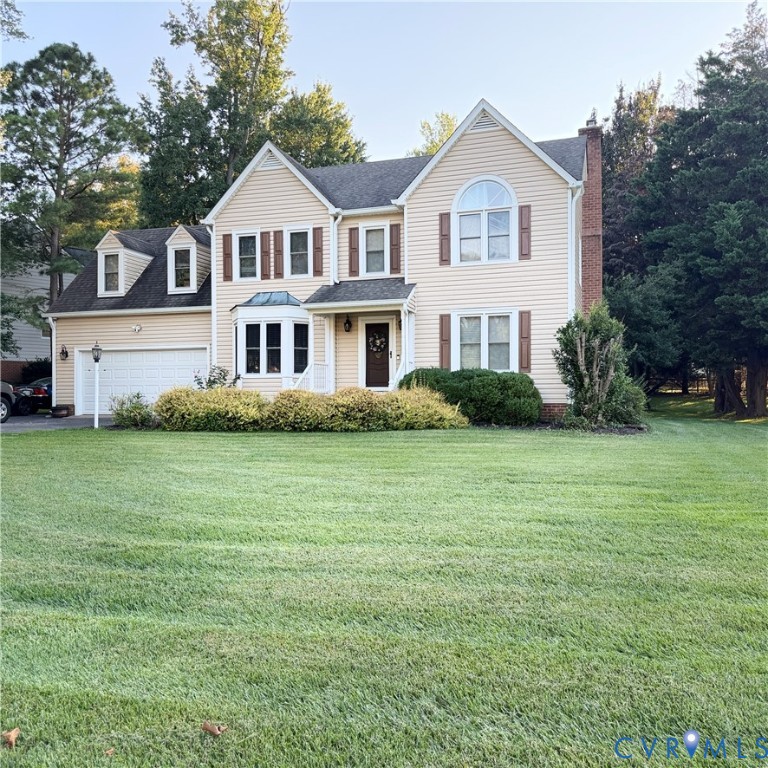 Traditional two-story home with light-toned siding, dark shutters, and a prominent front gable