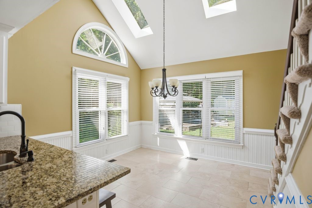 Vaulted ceiling with skylights, arched transom window, beadboard wainscoting, and a granite-finish countertop