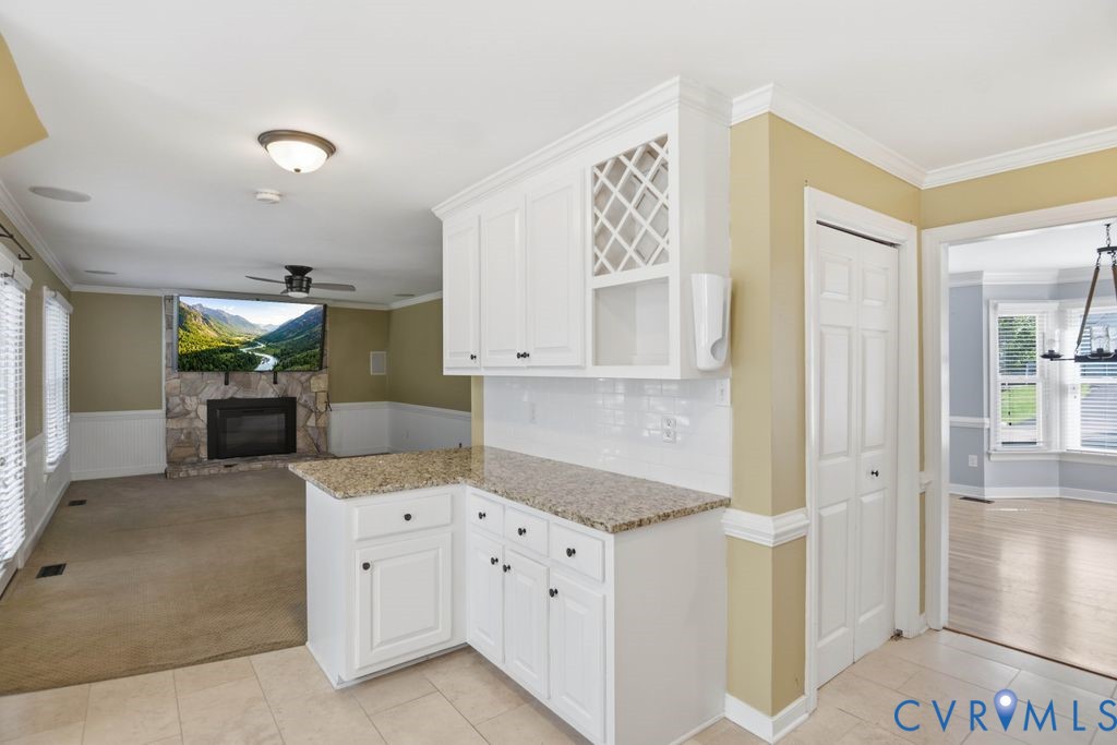 Built-in white cabinetry, light-toned countertop, and a stone-clad fireplace