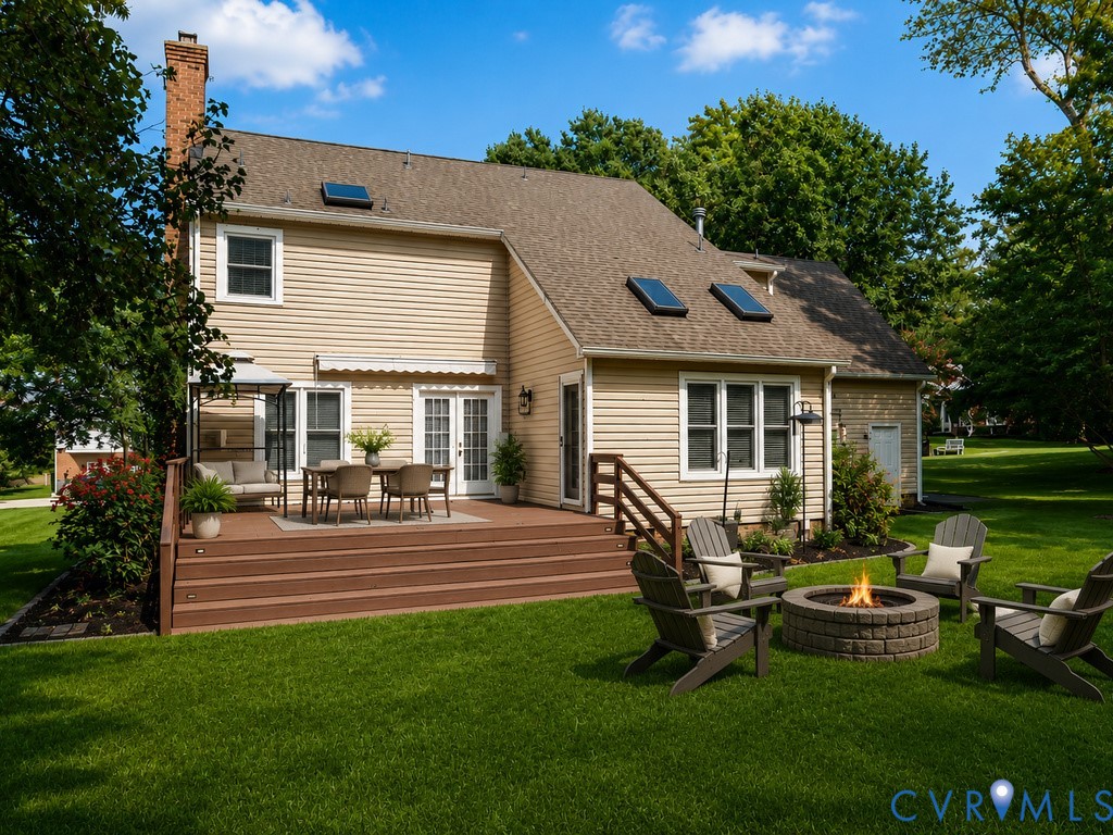 Expansive backyard featuring a multi-level deck, lush lawn, and a built-in stone fire pit