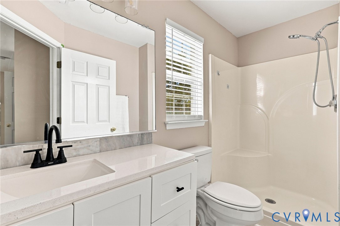 White vanity with a single basin sink, matte black faucet, and stone countertop
