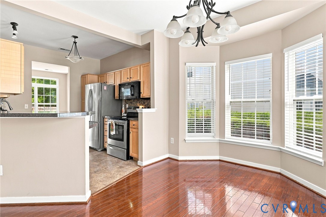 Bay window with multiple double-hung windows, wood-finish flooring, and a decorative chandelier Bay window with multiple double-hung windows, wood-finish flooring, and a decorative chandelier